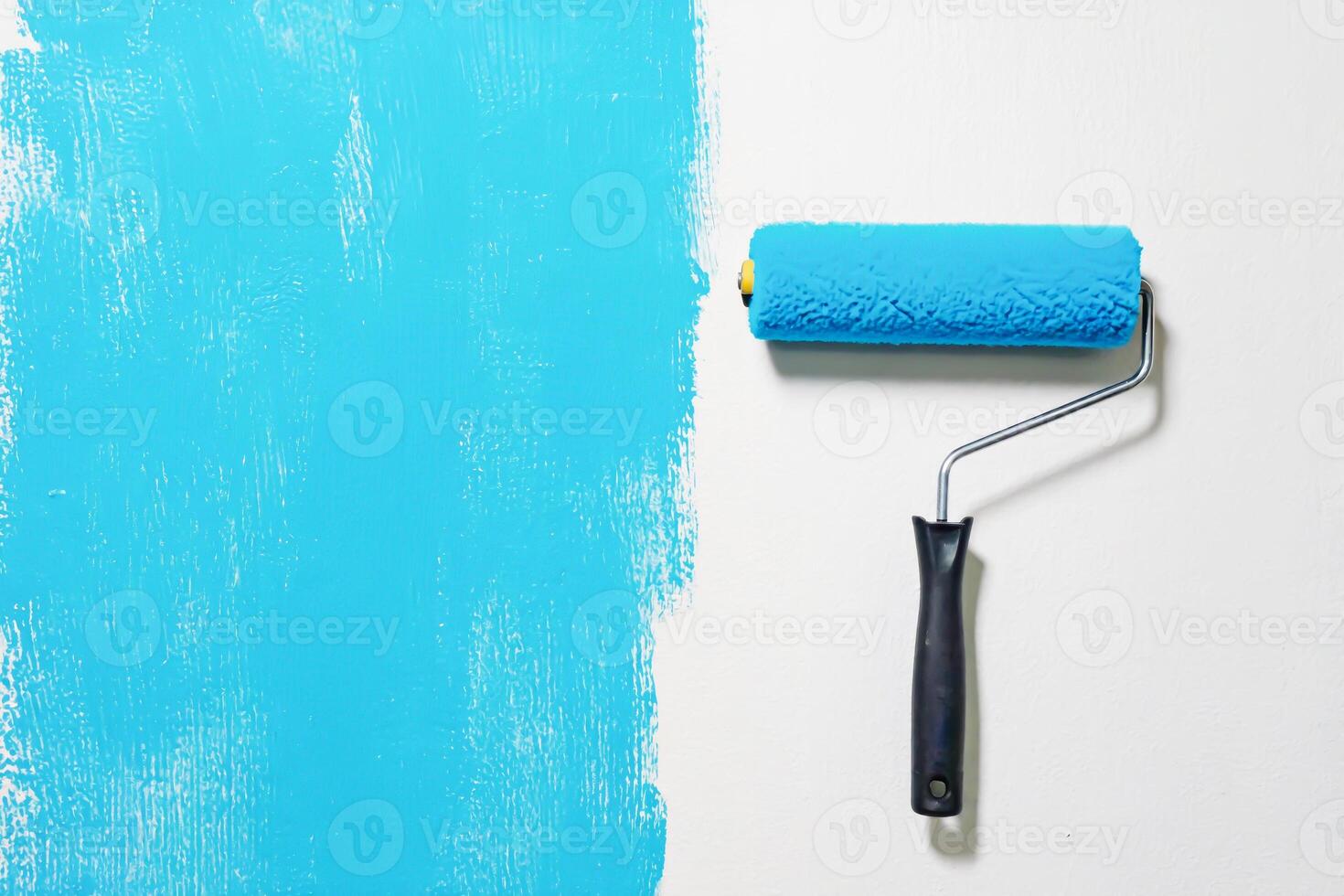 Paint roller near turquoise stroke on white surface photo