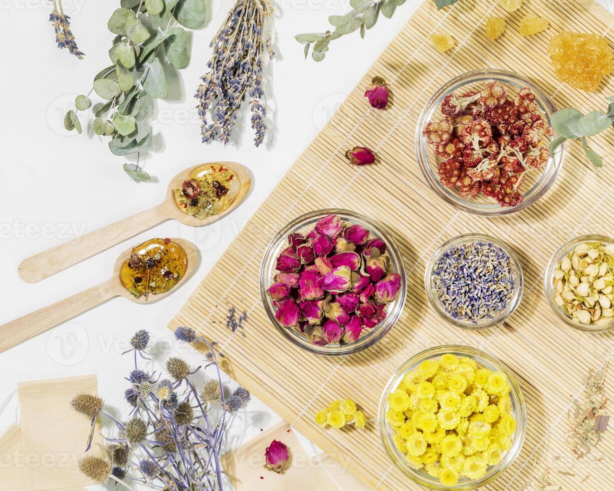 Dry flowers and herbs, tea bags and wooden spoons on wooden napkin photo