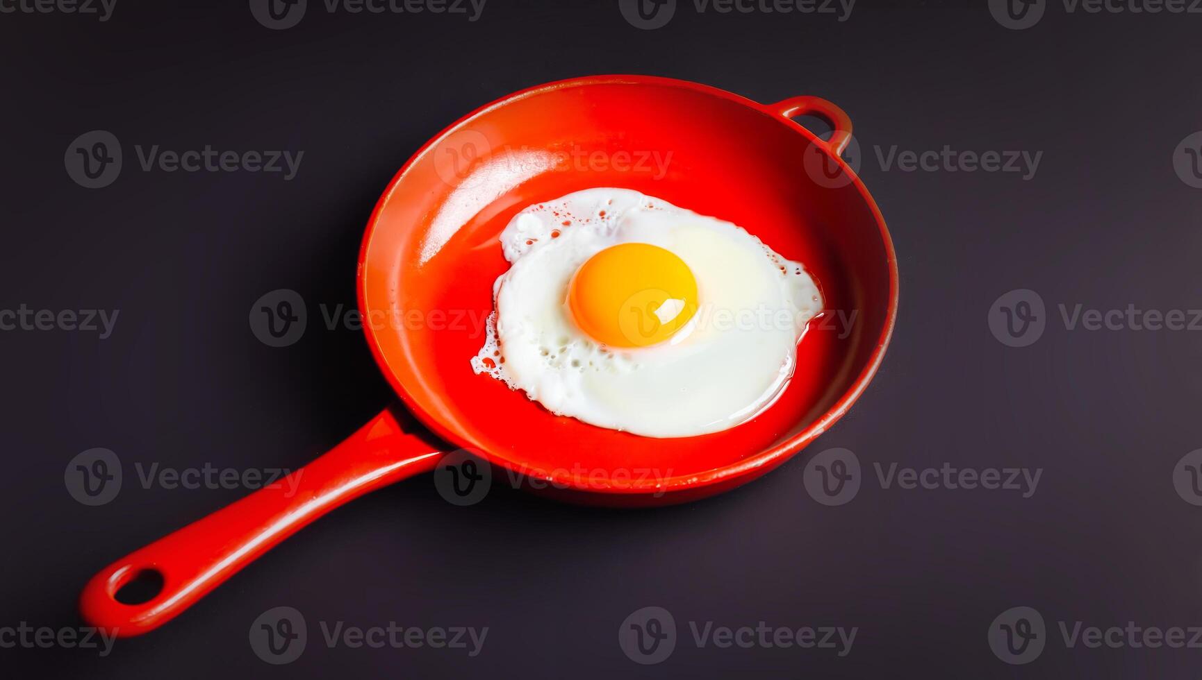 Sunny side up egg in bold red skillet on dark background photo