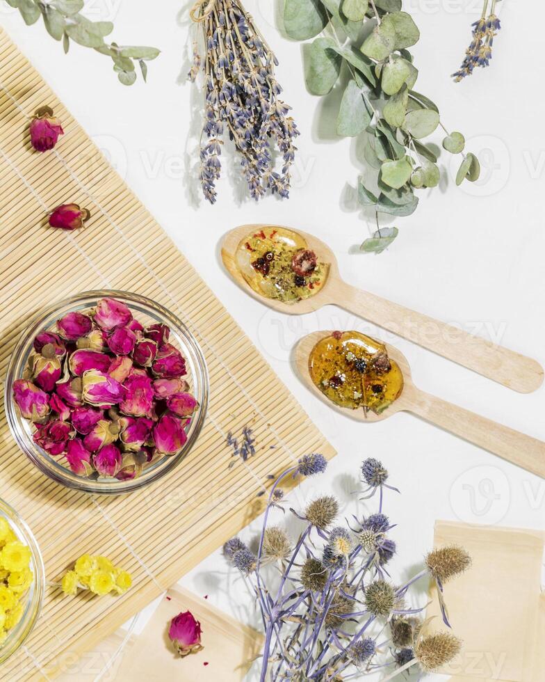 herbal apothecary concept with dry flowers and herbs, tea bags and wooden spoons photo