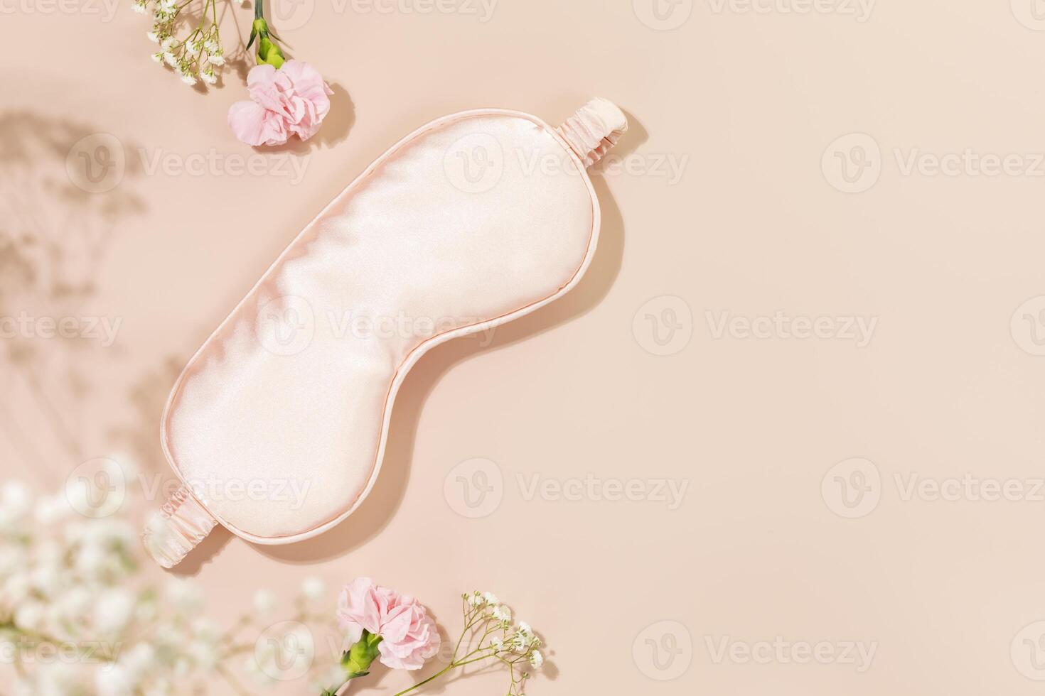 Pink mask for sleep and tender spring flowers on pink background with copy space photo