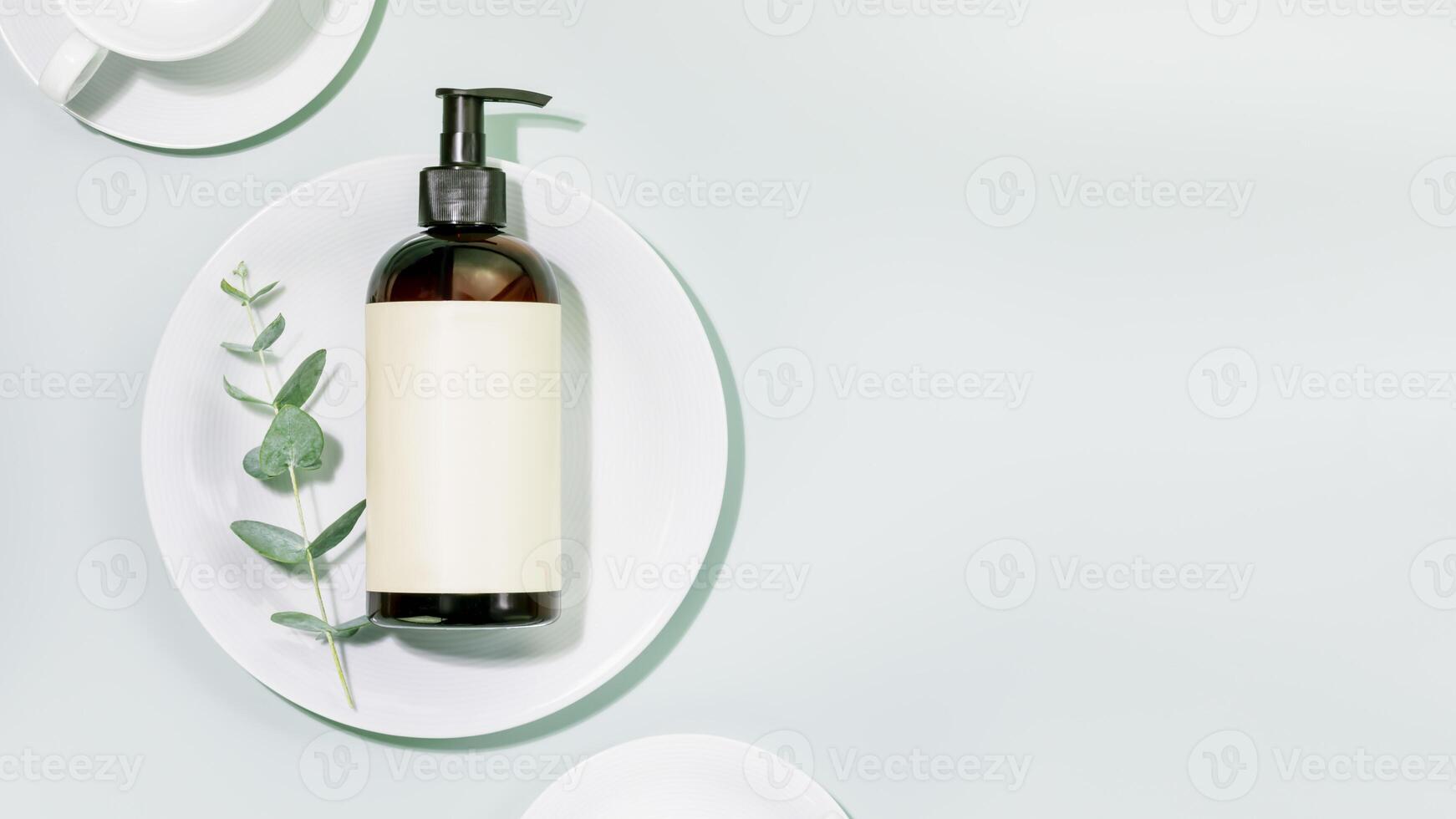 Bottle with dish detergent on clean plate on blue background with copy space photo