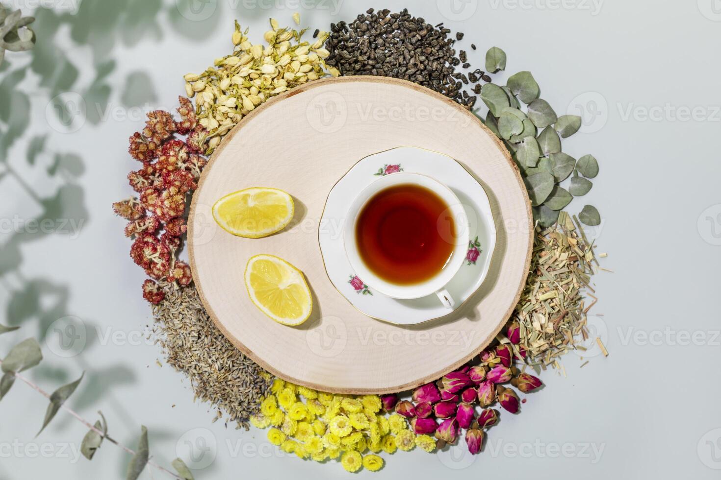 Still life with dry wild growing flowers, herbs, cup of tea and lemon slices photo