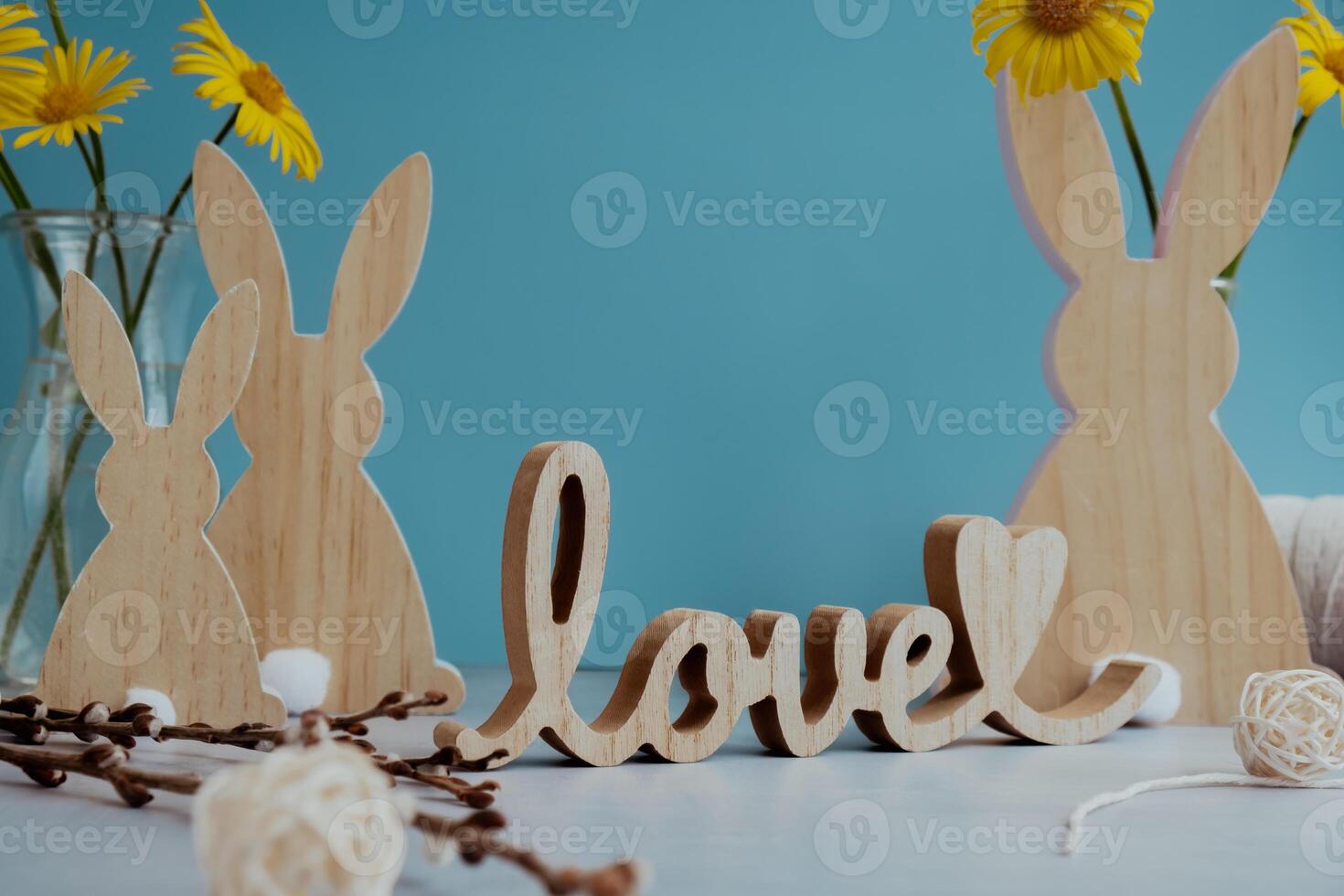 Wooden word LOVE with bunny figures eggs and fresh flowers. Easter composition content still life. Christian symbols of spring holiday photo