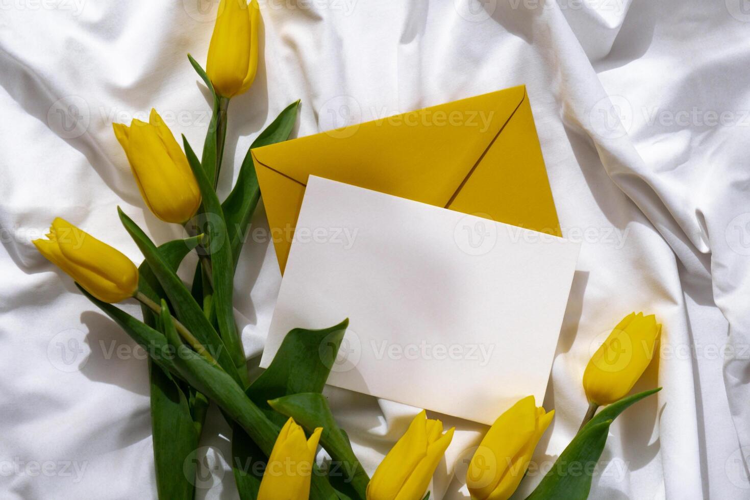 Bouquet of yellow tulips in craft paper bag on messy bed with white empty copy space postcard template. Romantic morning scene. Greeting card Holiday flowers springtime atmosphere photo