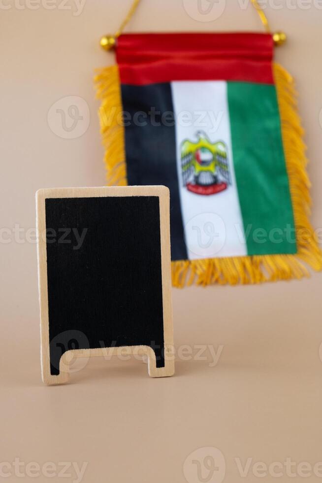 Empty blackboard sample Small flag of UAE on beige background with colorful envelopes. Copy space. Mock up advertisement template. Tourism travel voucher with United Arab Emirates national symbol. Visit Dubai concept photo