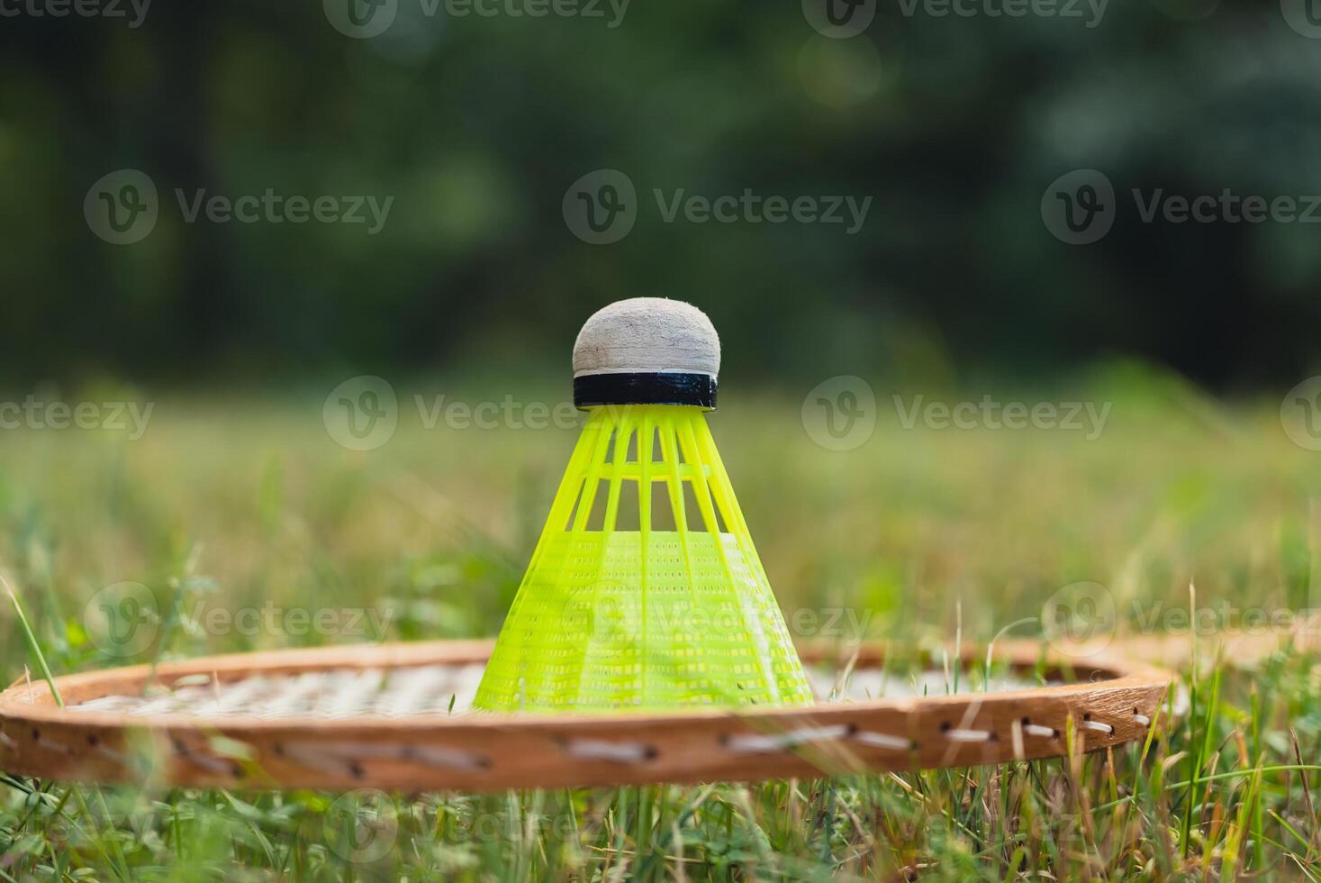 Neon yellow badminton shuttlecock and racket on green grass outdoors. Copy space soft selective focus on shuttlecocks. Alternative fitness recreational sport photo
