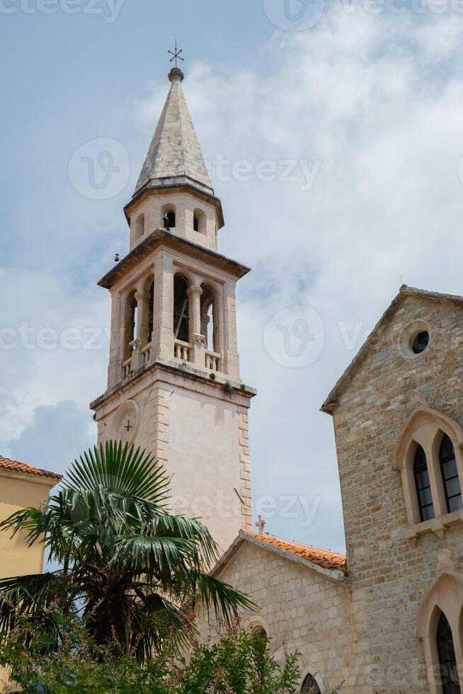 Budva, Montenegro picturesque old town and fortress walls architecture. Stunning showcasing historic stone buildings with red-tiled roofs traditional house. Spire of the chapel of The Church of Sveti Ivan. Sea coastline travel tourist destination photo