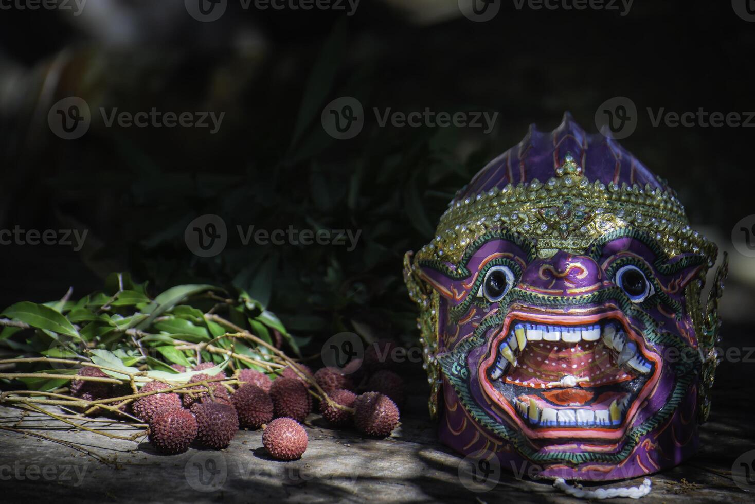 Khon is a rare Thai cultural performance. The image shows a purple monkey head mask and red fruits. photo