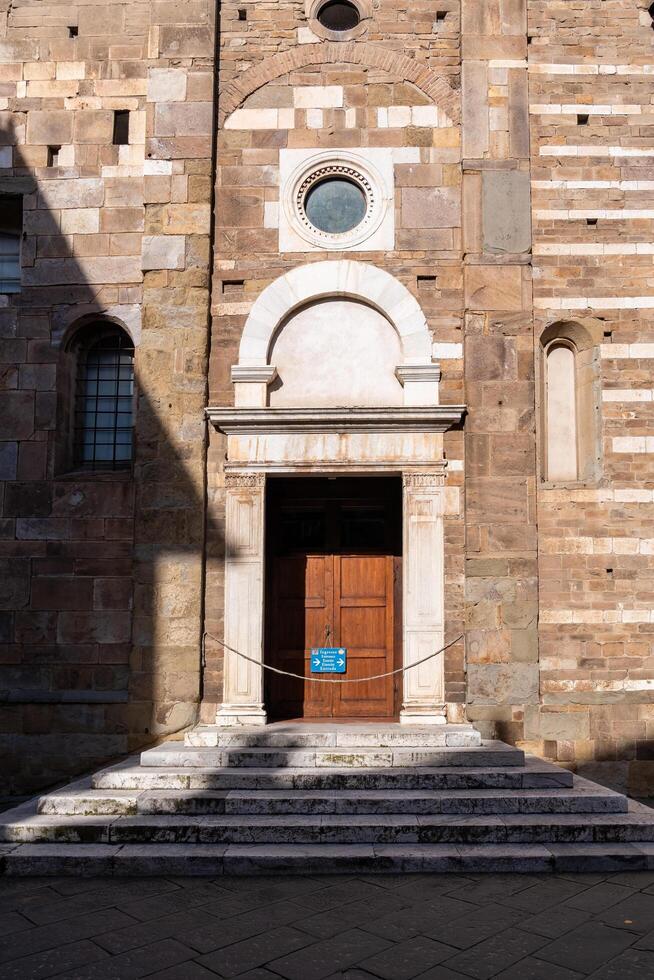 Lucca, Italy-February 16, 2025-vertical photograph of side door of the Basilica of San Frediano in Lucca during a sunny day photo