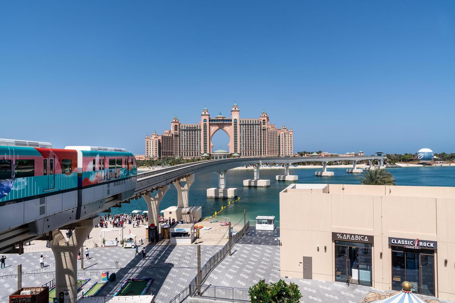 Dubai, United Arab Emirates - March 17, 2023-The monorail that takes tourists to visit Palm Jumeirah and in the background the famous Atlantis Hotel during a sunny day photo