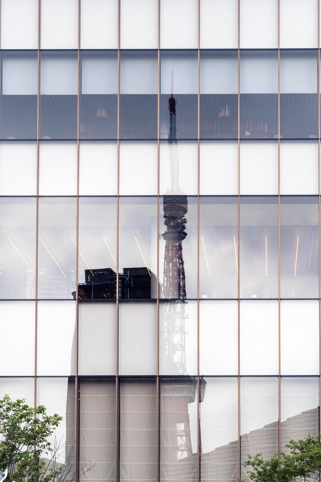 Tokyo, Japan-august 6, 2024-The famous Tokyo Tower is reflected in the glass windows of Azabudai hills on a cloudy day. photo