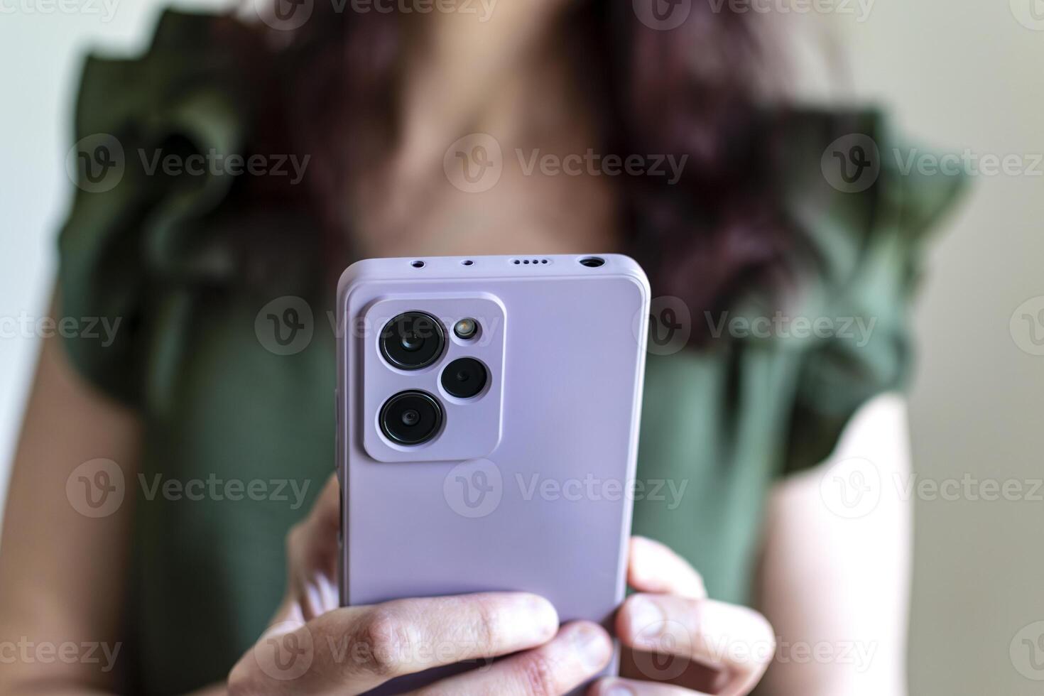 Woman in green tank top holding smartphone with purple case, business concept, browsing photo