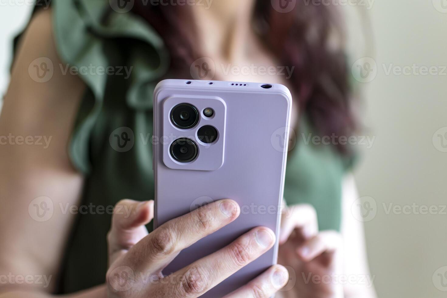 Woman in green tank top holding smartphone with purple case, business concept, cell photo