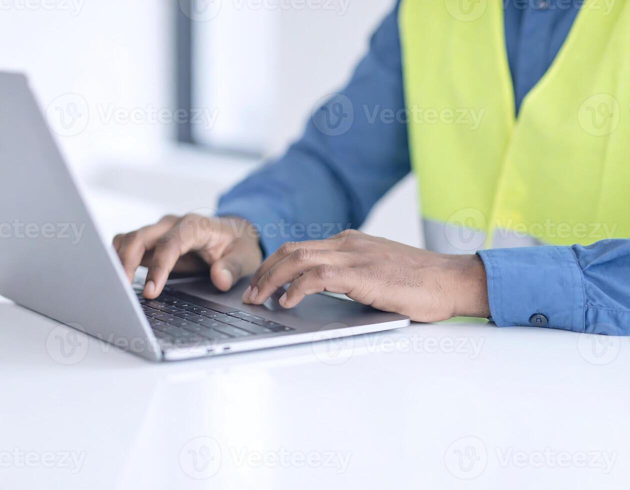 Unrecognizable Man in Safety Vest and Suit Using Laptop at Office Desk photo