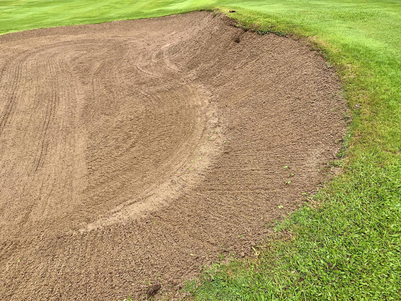 Golf Course Sand Pit Bunkers, green grass surrounding the beautiful sand holes is one the most challenging obstacles for golfers and adds to the beauty of the golf course. photo