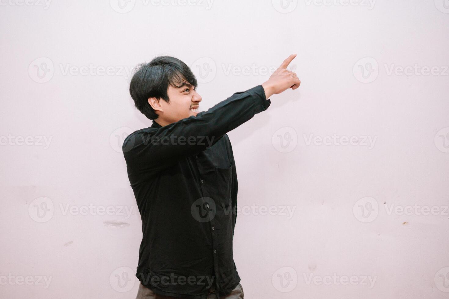 Enthusiastic asian man pointing towards something amazing upward photo