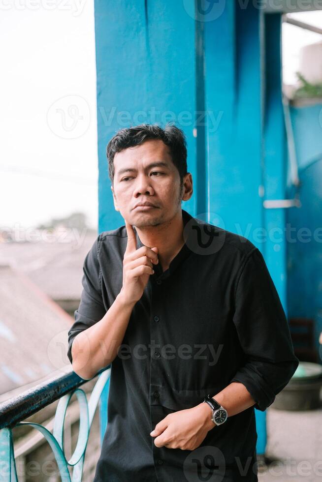 Thoughtful asian man with hand on chin looking away outdoor photo