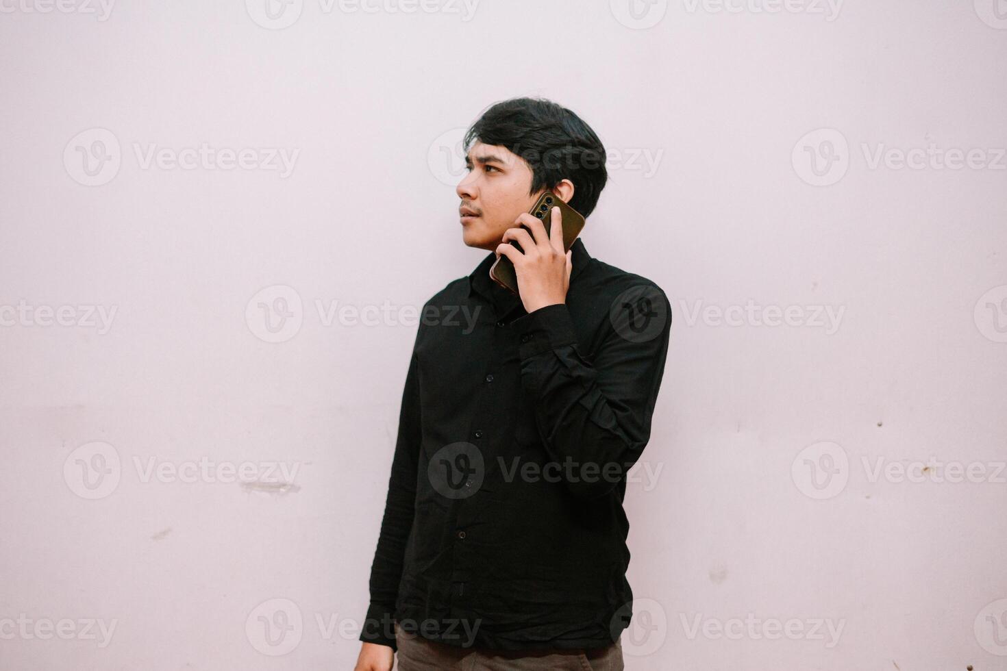 Pensive Young Man in Black Shirt Answering His Smartphone Overthinking photo