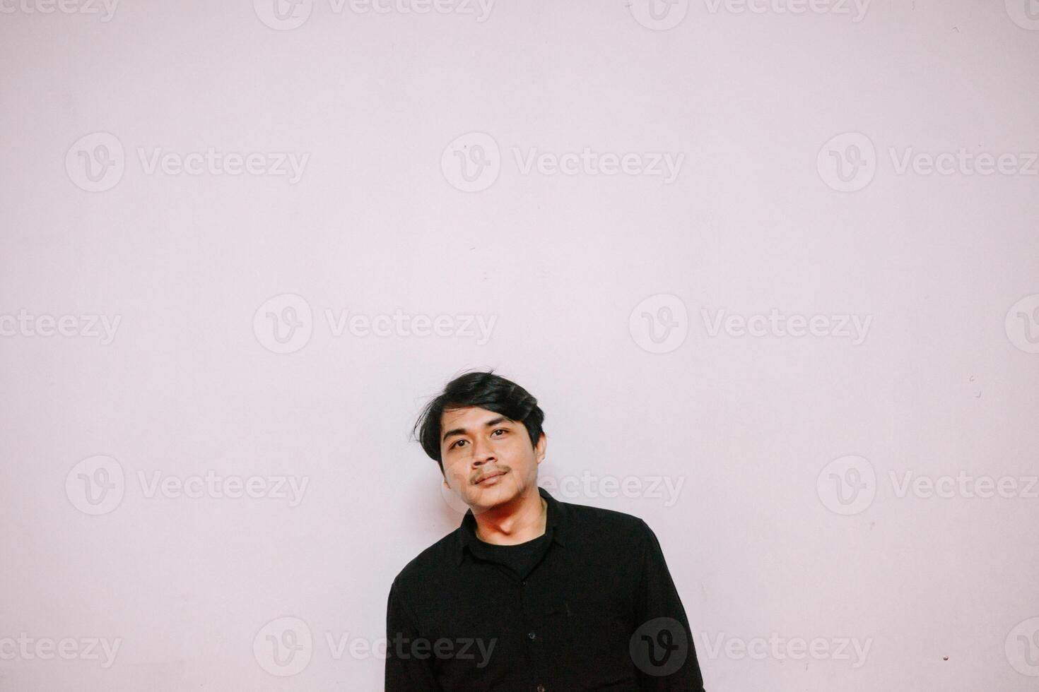 Contemplative portrait of a young man against a minimalist blank wall backdrop photo