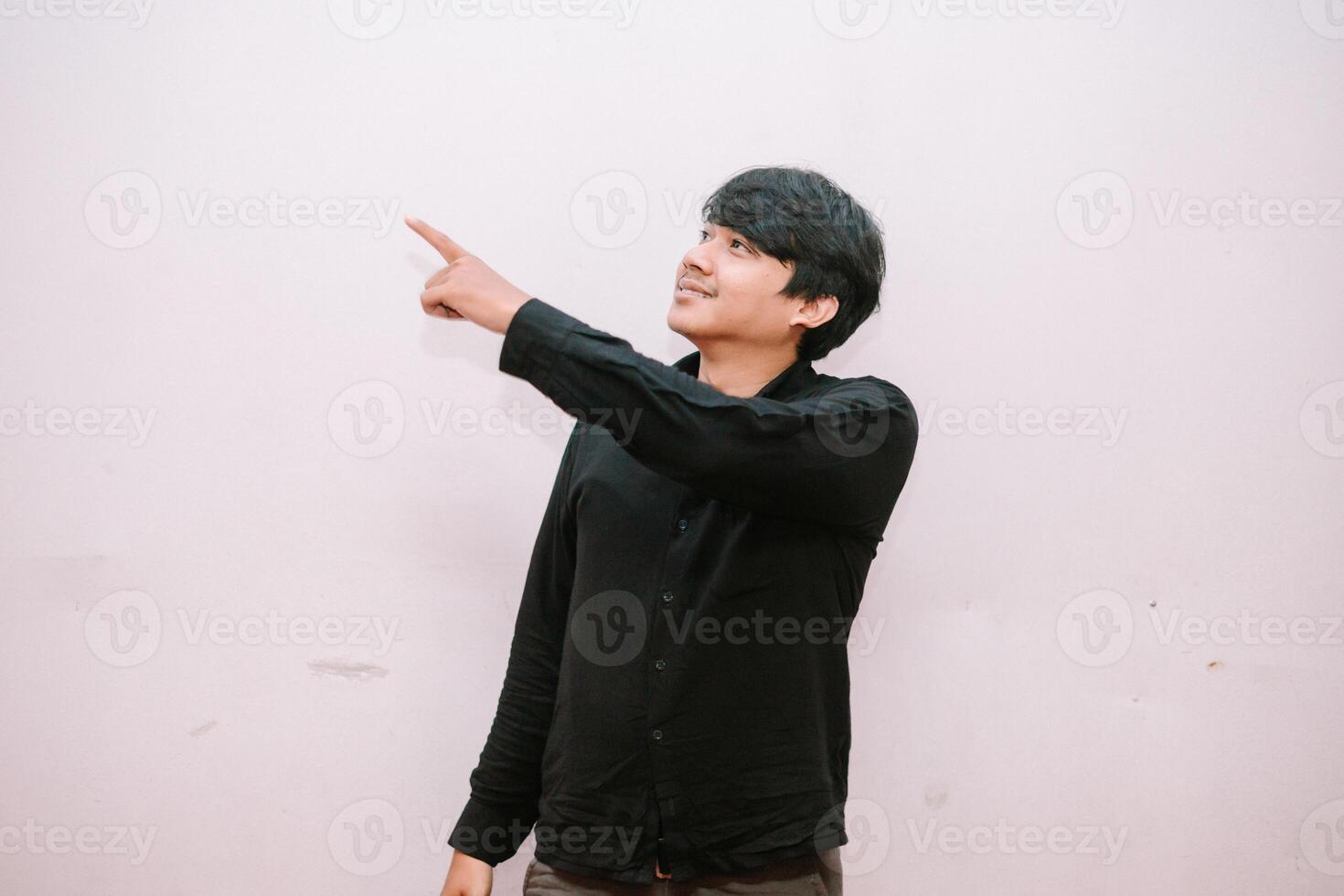 Young man pointing to something up above on clean isolated backdrop photo
