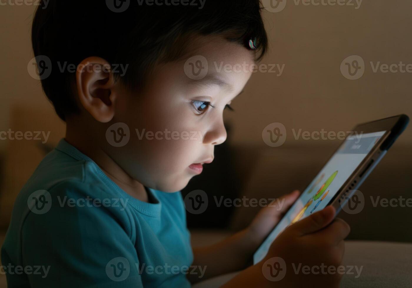 Captivated toddler exploring tablet in low light environment photo