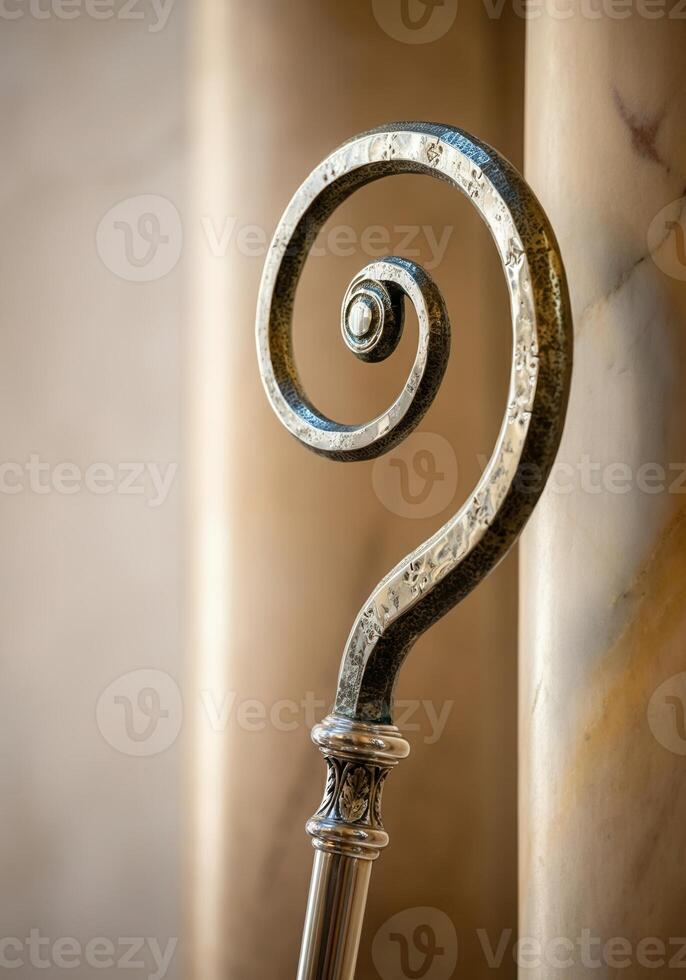 Ornate Tip of a crozier bishop staff against marble pillar in soft light photo