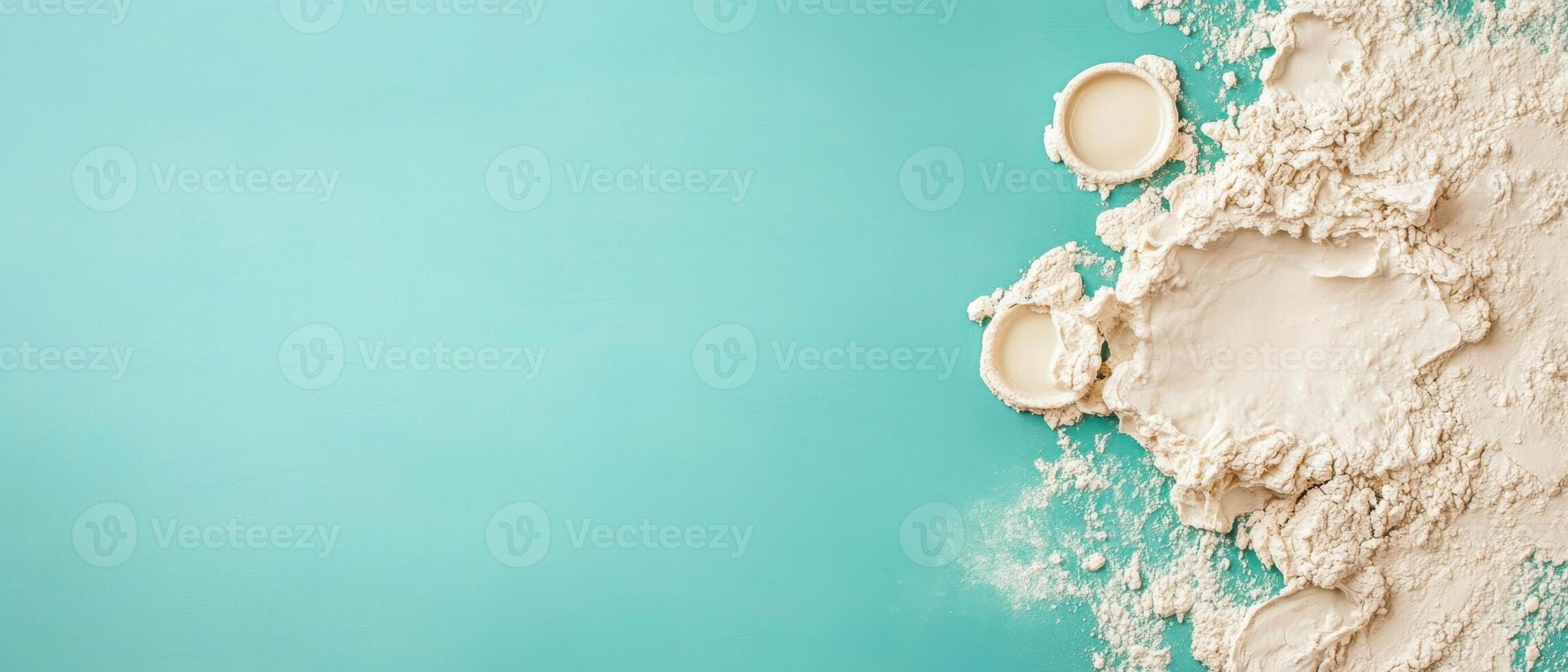 White powder heap with round molds lying on a clean light blue surface. Material spread loosely. Copy space on left side. photo