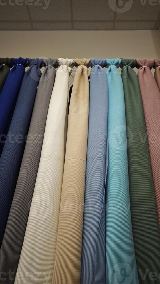 Assorted solid-colored fabrics hanging vertically photo