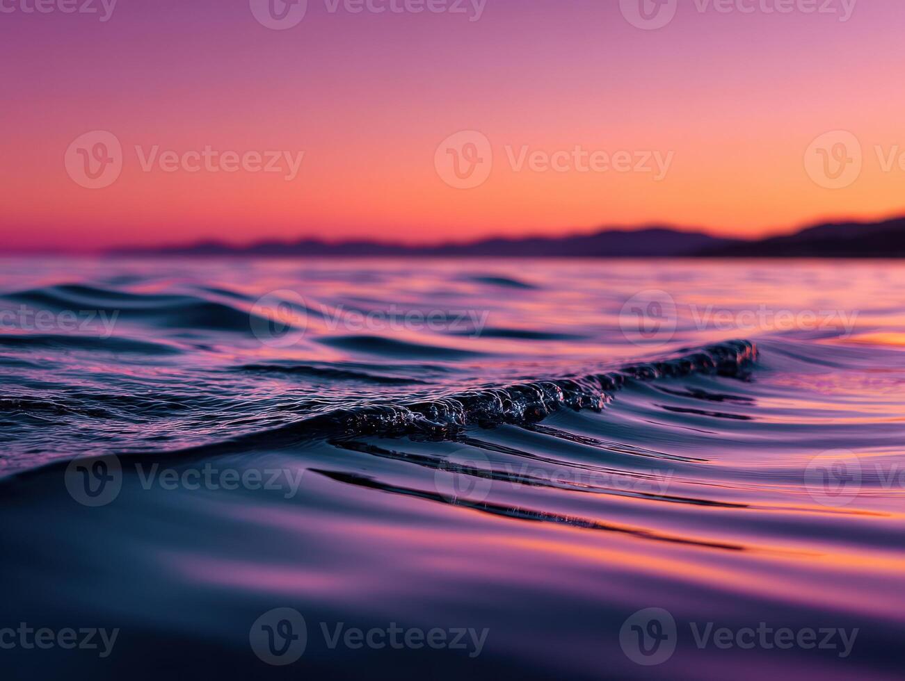 Waves gently lap the shore at sunset by the sea photo