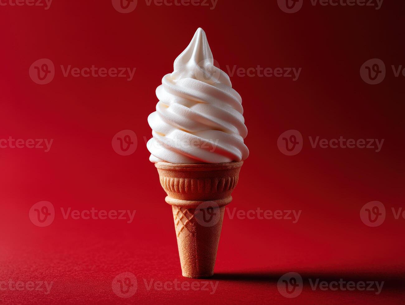 Swirled soft serve ice cream in a cone against a red backdrop photo
