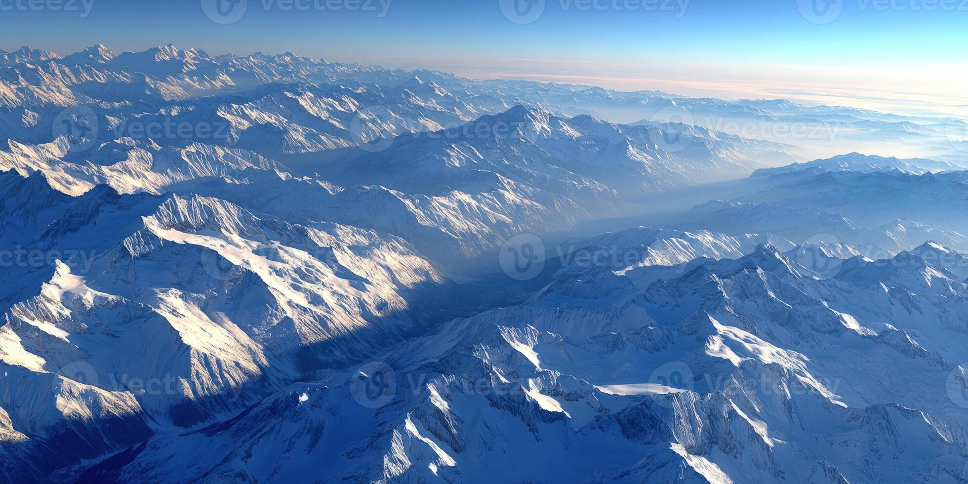Majestic snowy mountains under a clear blue sky at dawn photo