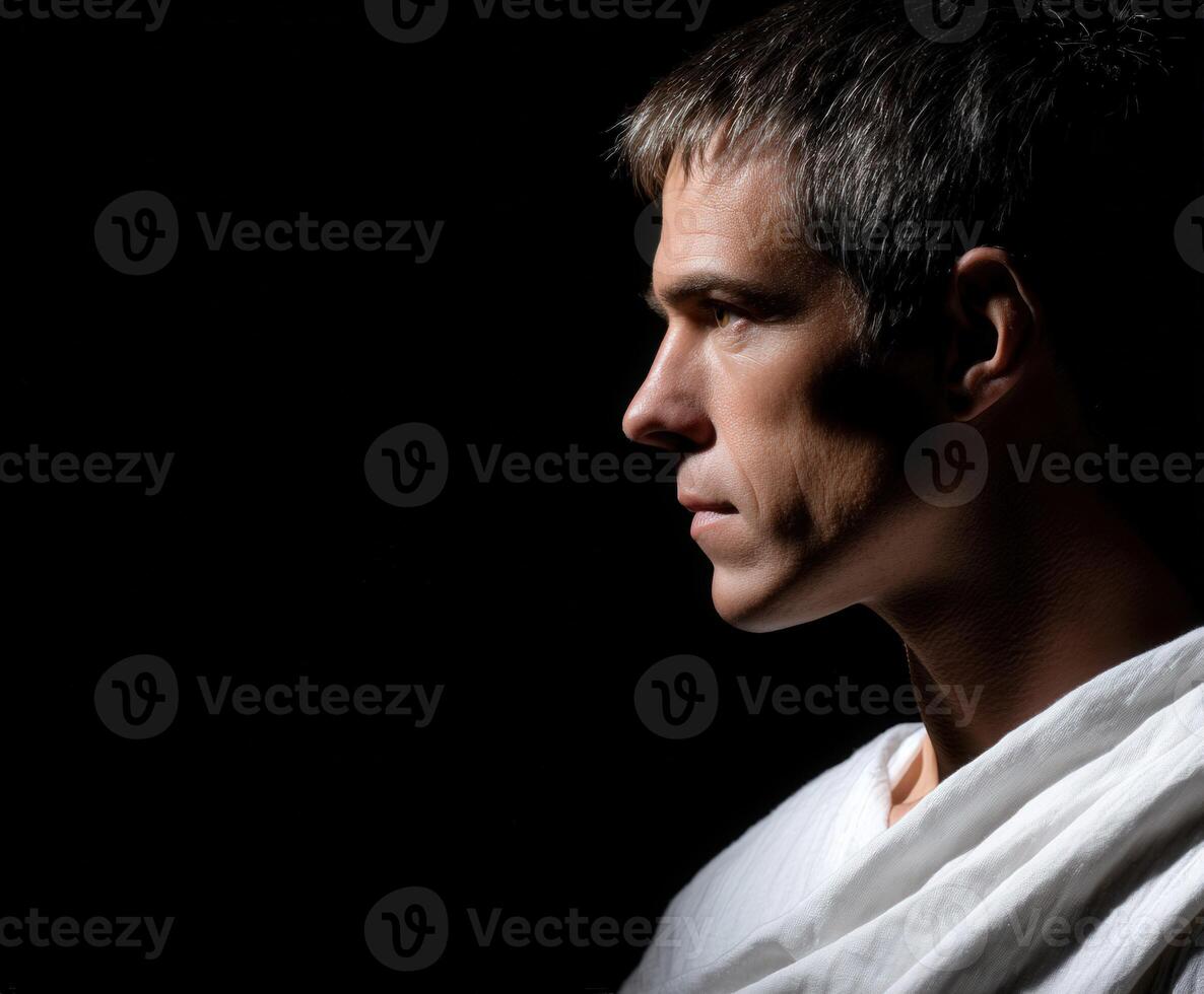 Stoic man in contemplation against a dark background expressing deep thoughts photo