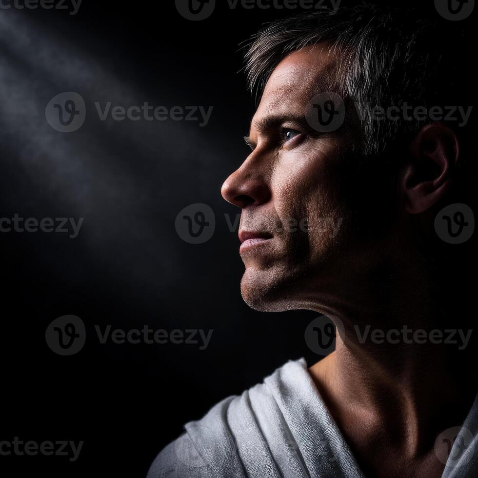 Stoic man in profile illuminated by soft light, expressing deep contemplation photo