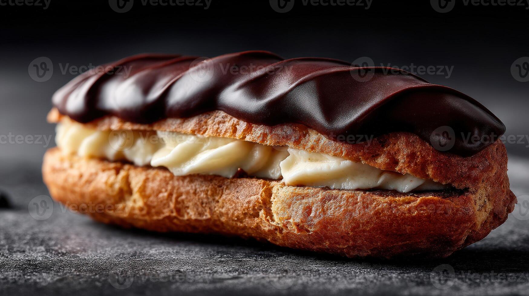 Delicious chocolate eclair displayed on a dark countertop photo