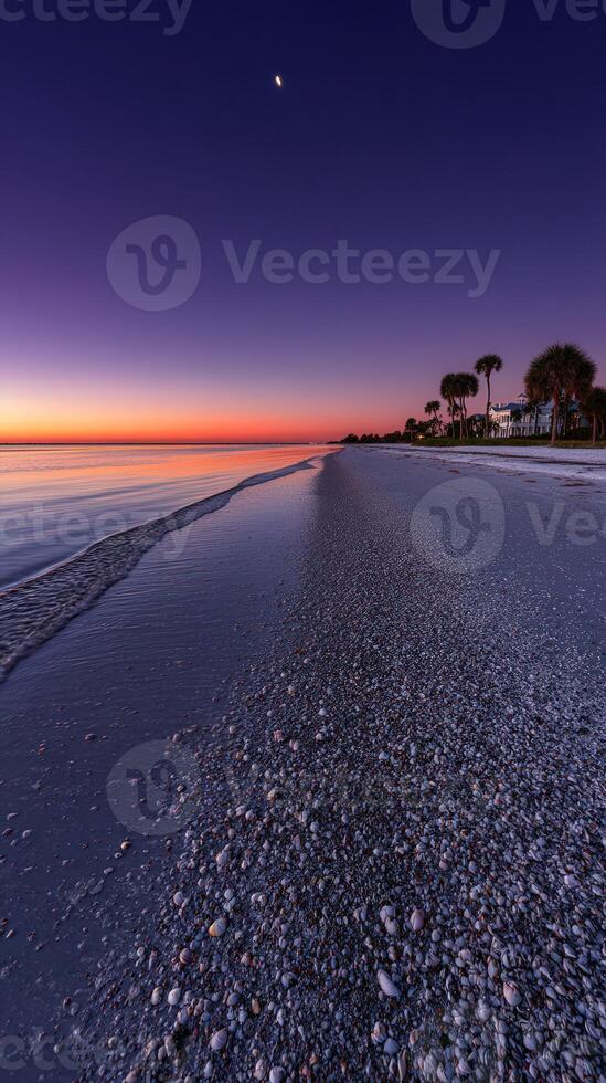 Sunset over serene beach with gentle waves and a distant moon photo