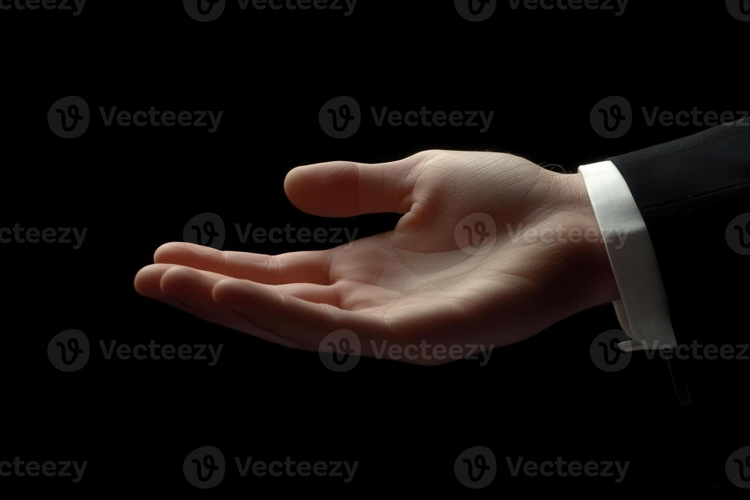 Elegant open hand gesture in a dark setting, symbolizing invitation or offering photo