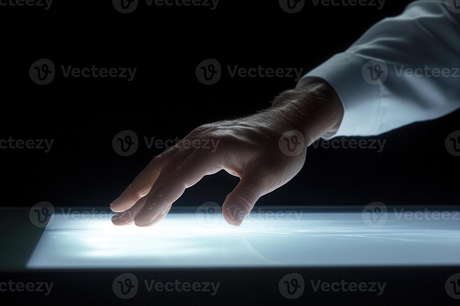 A human hand gently touches a glowing surface, creating an ethereal light effect in darkness photo