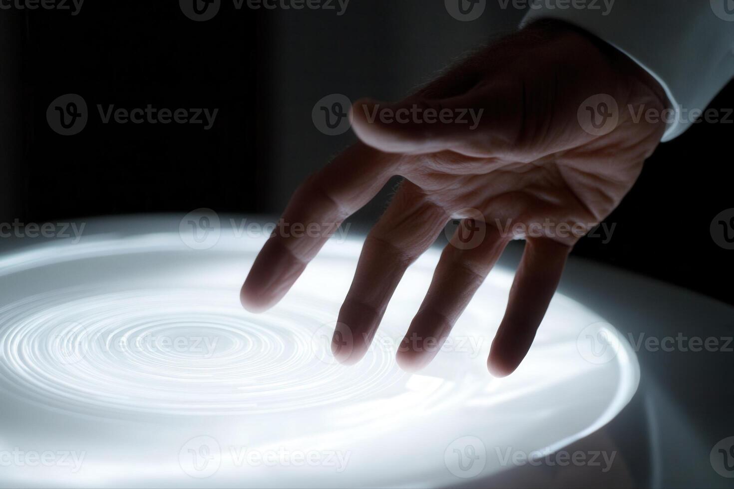 A human hand gently interacts with a glowing circular light display, creating mesmerizing patterns photo