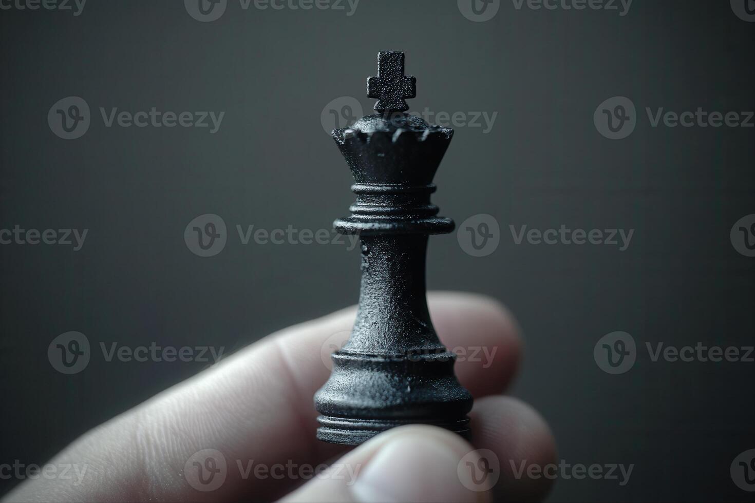 A close-up of a hand holding a black chess king piece against a dark background photo