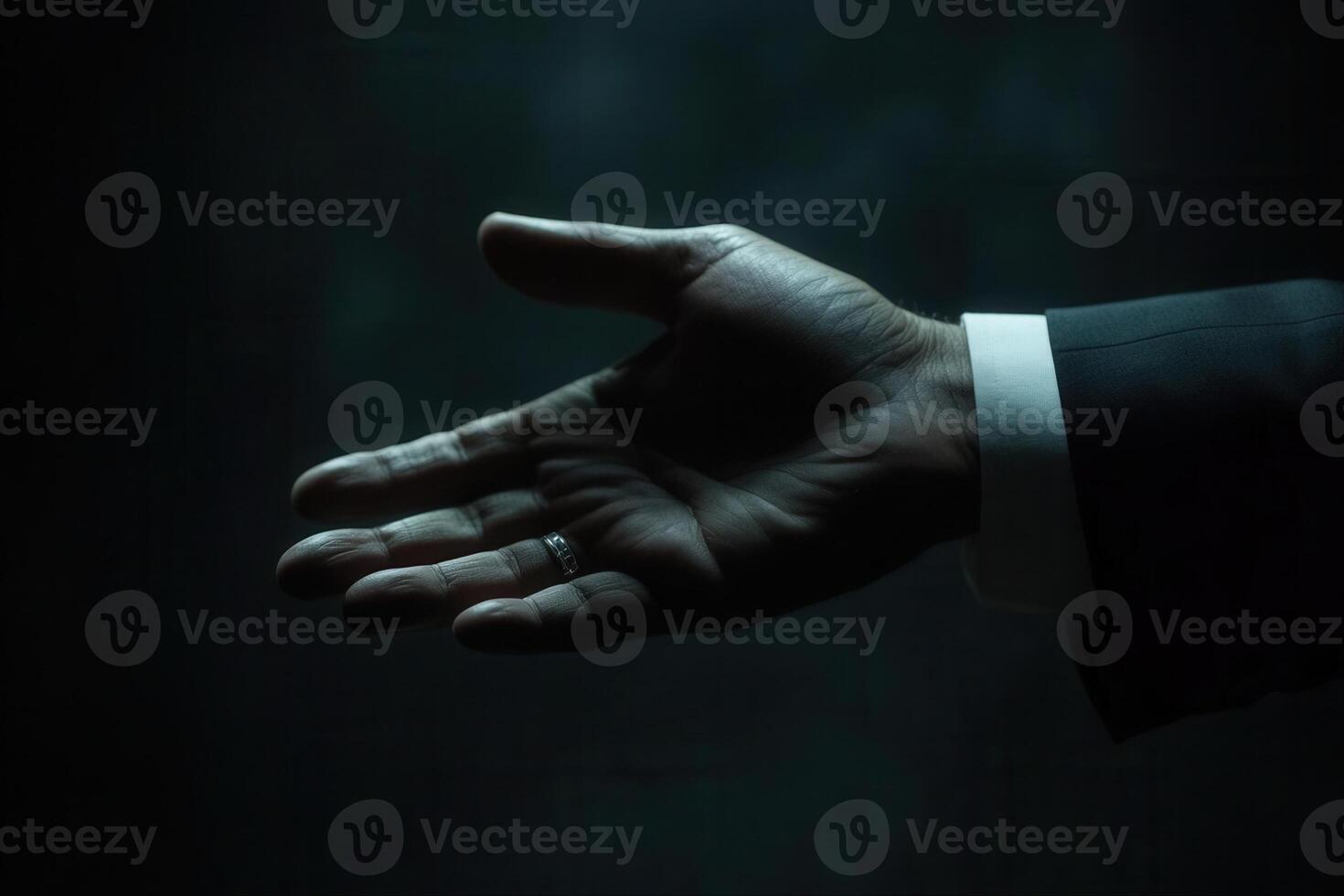A businessman's outstretched hand reaching out in a dimly lit environment, symbolizing opportunity photo