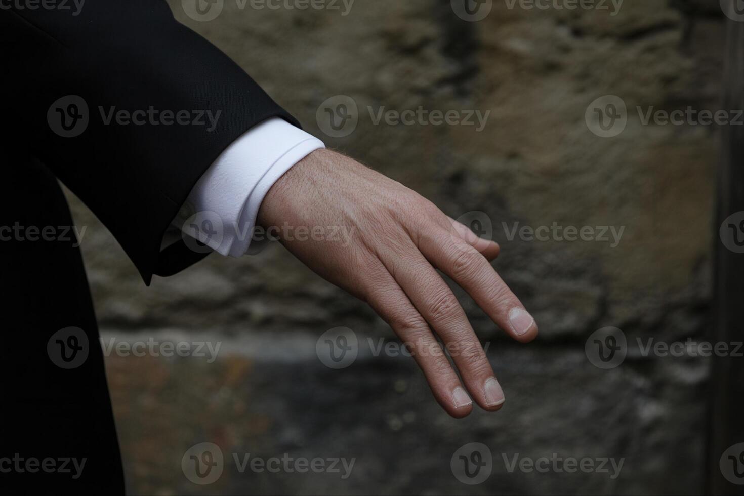 Elegant hand gesture of a man in a suit against a textured stone wall background photo