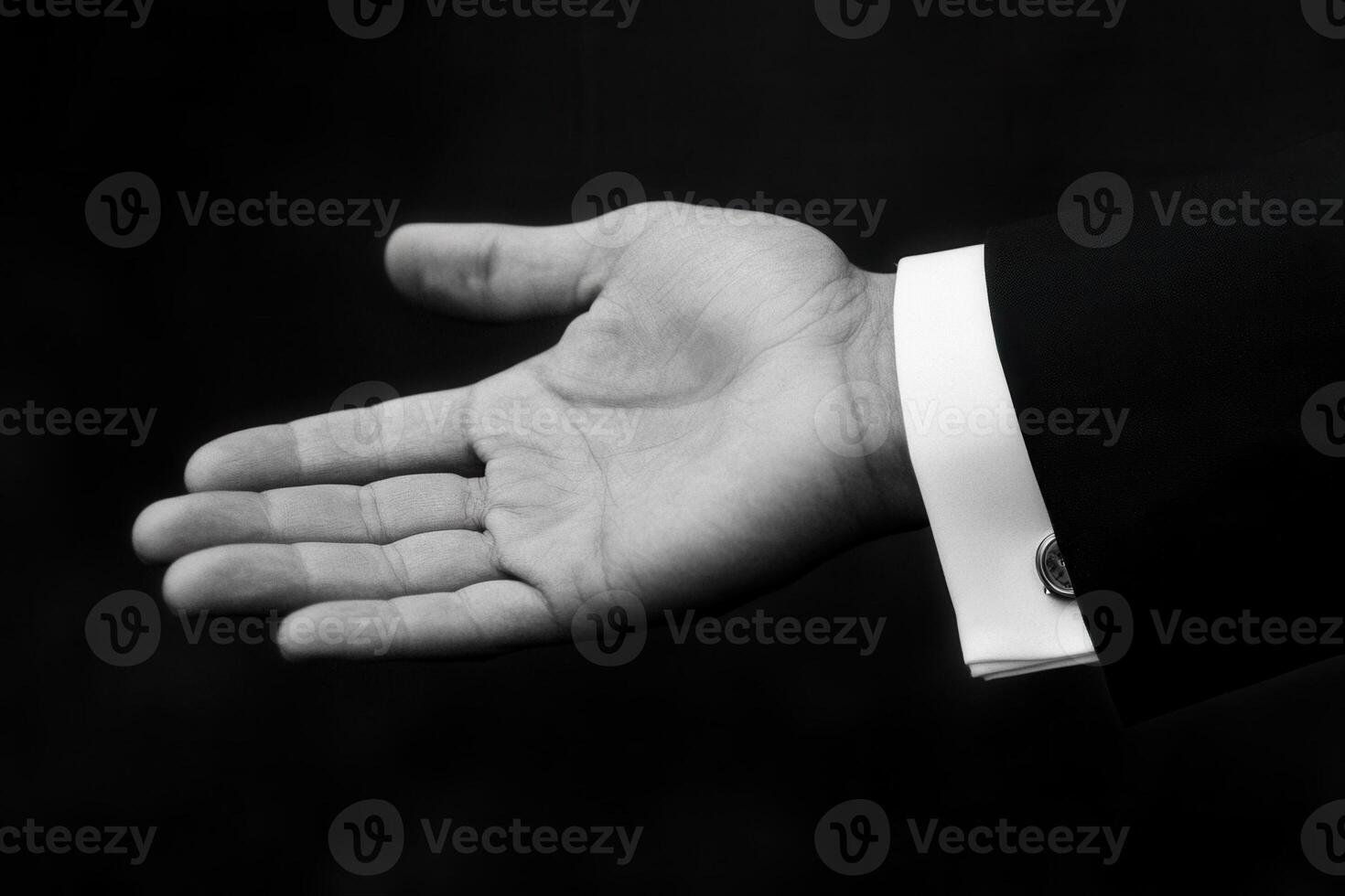 Elegant black and white image of a man's outstretched hand in a formal suit against a dark backdrop photo