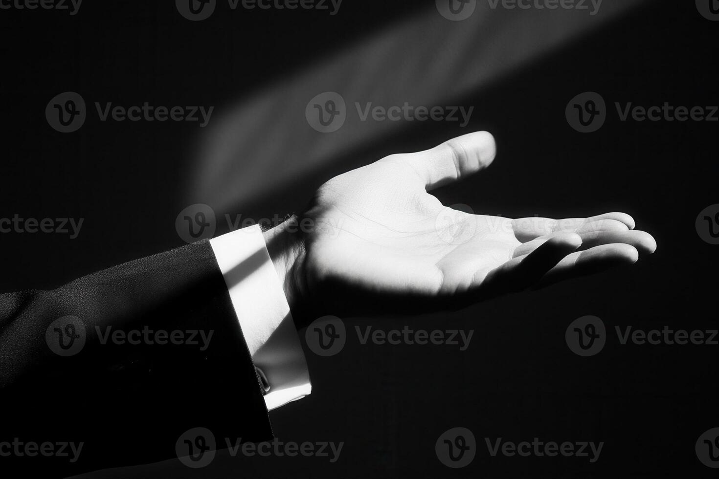 Elegant hand gesture in formal attire reaching out, illuminated by soft light photo