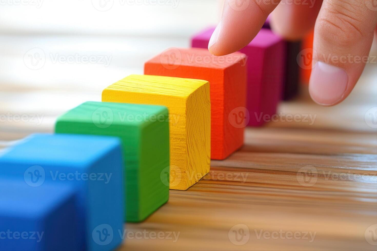 Colorful wooden blocks being arranged by a hand on a textured surface, showcasing creativity photo