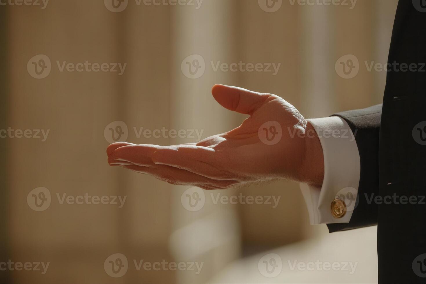 Elegant hand gesture of a suited individual against a blurred architectural backdrop photo