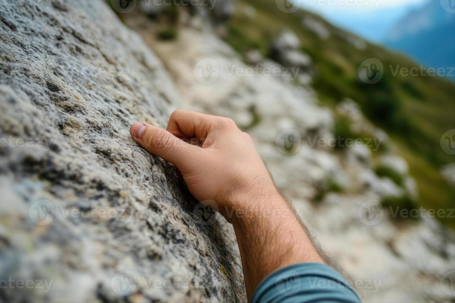 A climber's hand gripping a rocky surface on a mountain trail, with scenic nature backdrop photo
