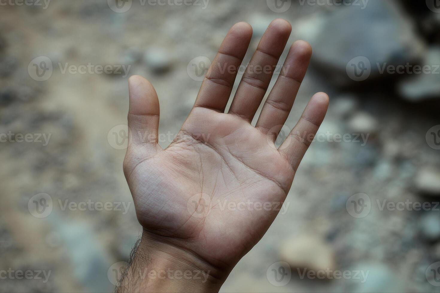 Close-up of an open human hand against a blurred rocky background, showcasing skin texture photo
