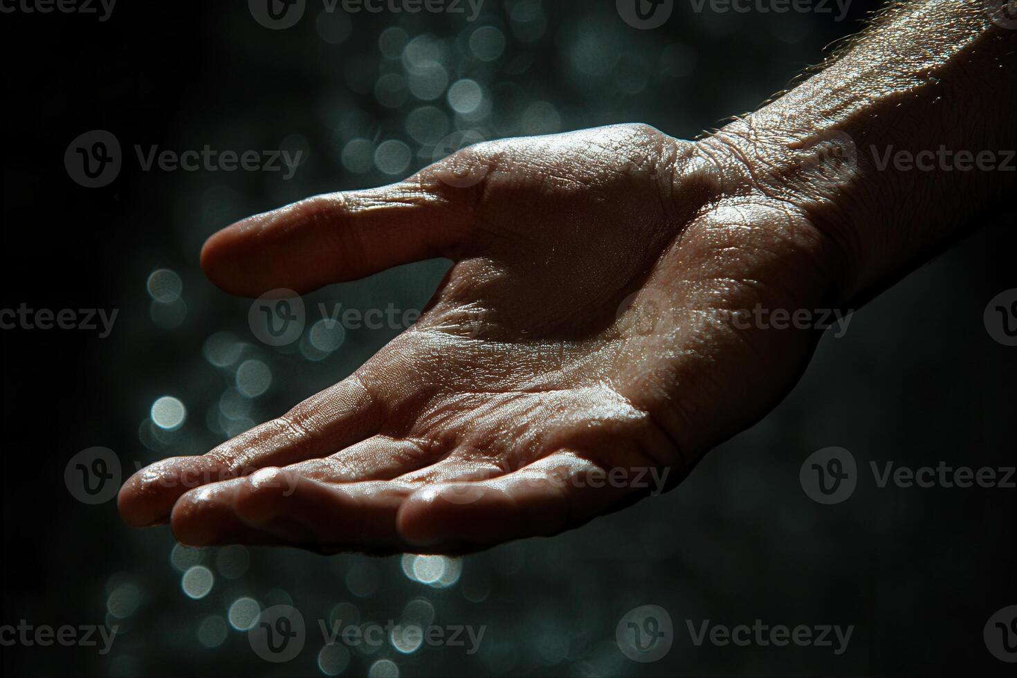 Close-up of a wet hand reaching out, with shimmering water droplets in the background photo