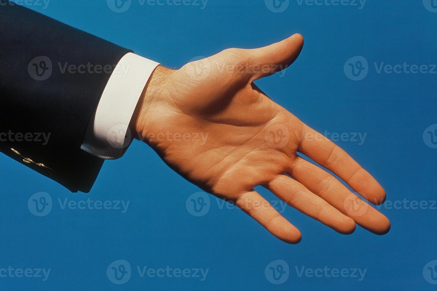 A business professional extends a hand for a handshake against a blue background photo